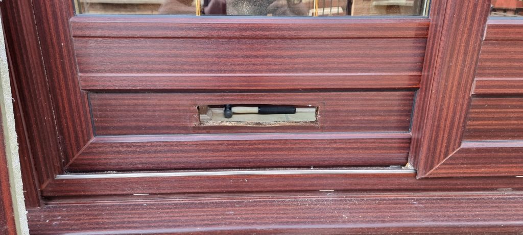 Rosewood uPVC door panel with the letterplate removed and the aperture damaged
