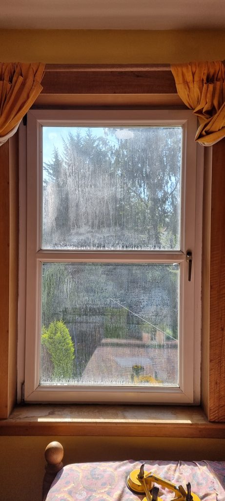 Woodgrain uPVC window with heavy misting and streaking between the panes
