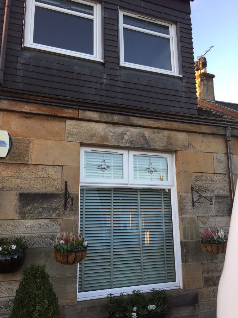 Sandstone house with an old white uPVC window and front door before replacement