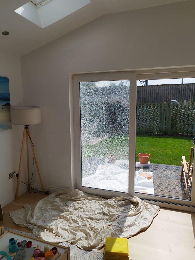 Patio door pane shattered into a crazed sheet of toughened glass, seen from the lounge