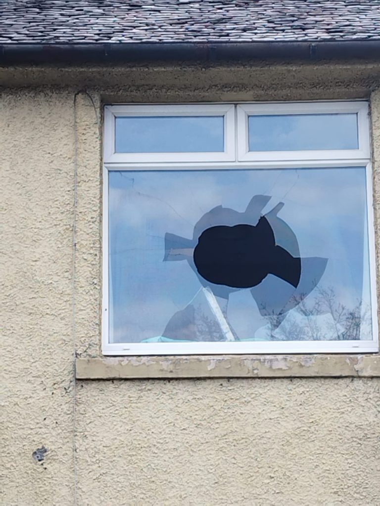 Upstairs window with a large hole smashed through the pane, waiting on new glass